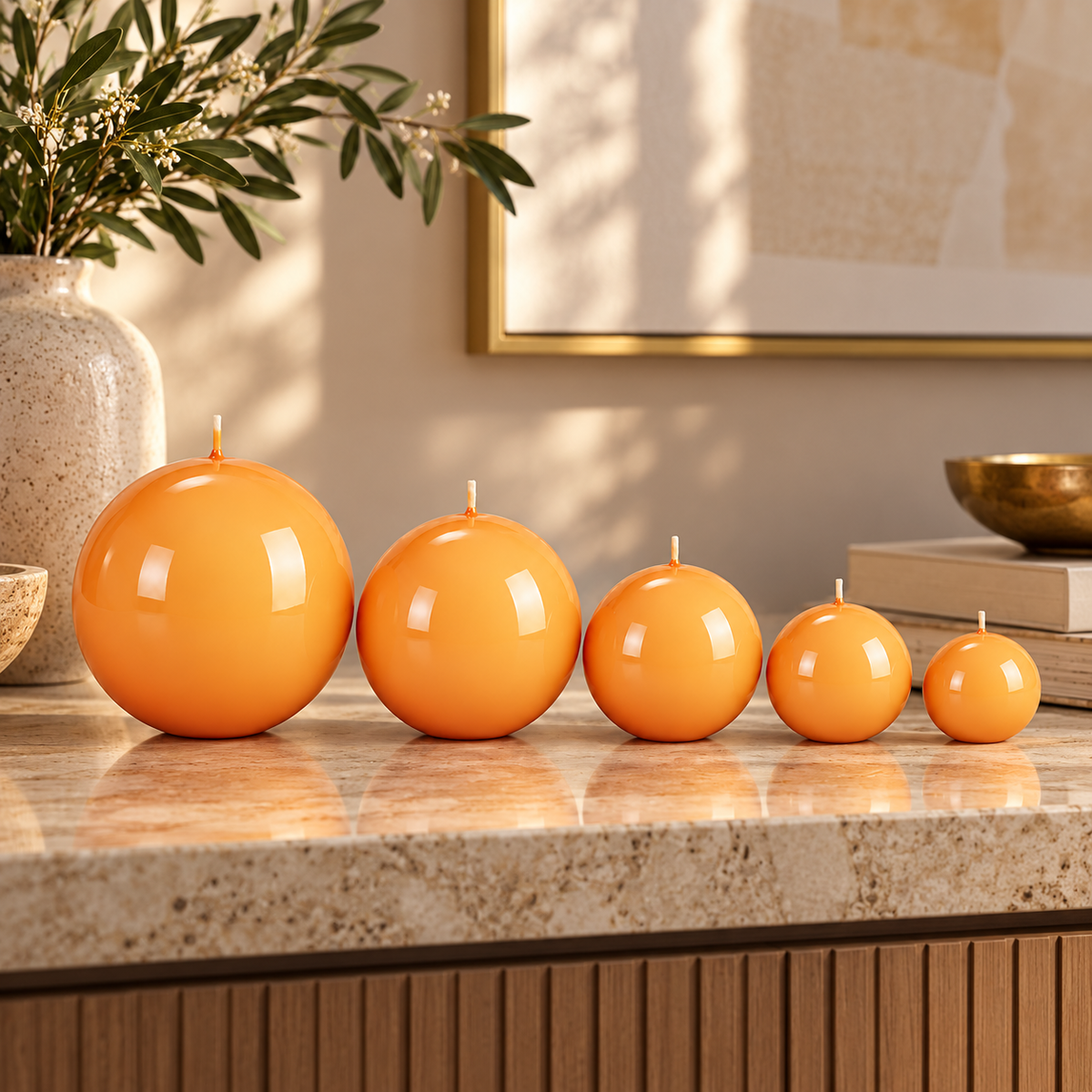 Candele sferiche Meloria arancio in cinque dimensioni, esposte su un piano in pietra in un interno elegante.
