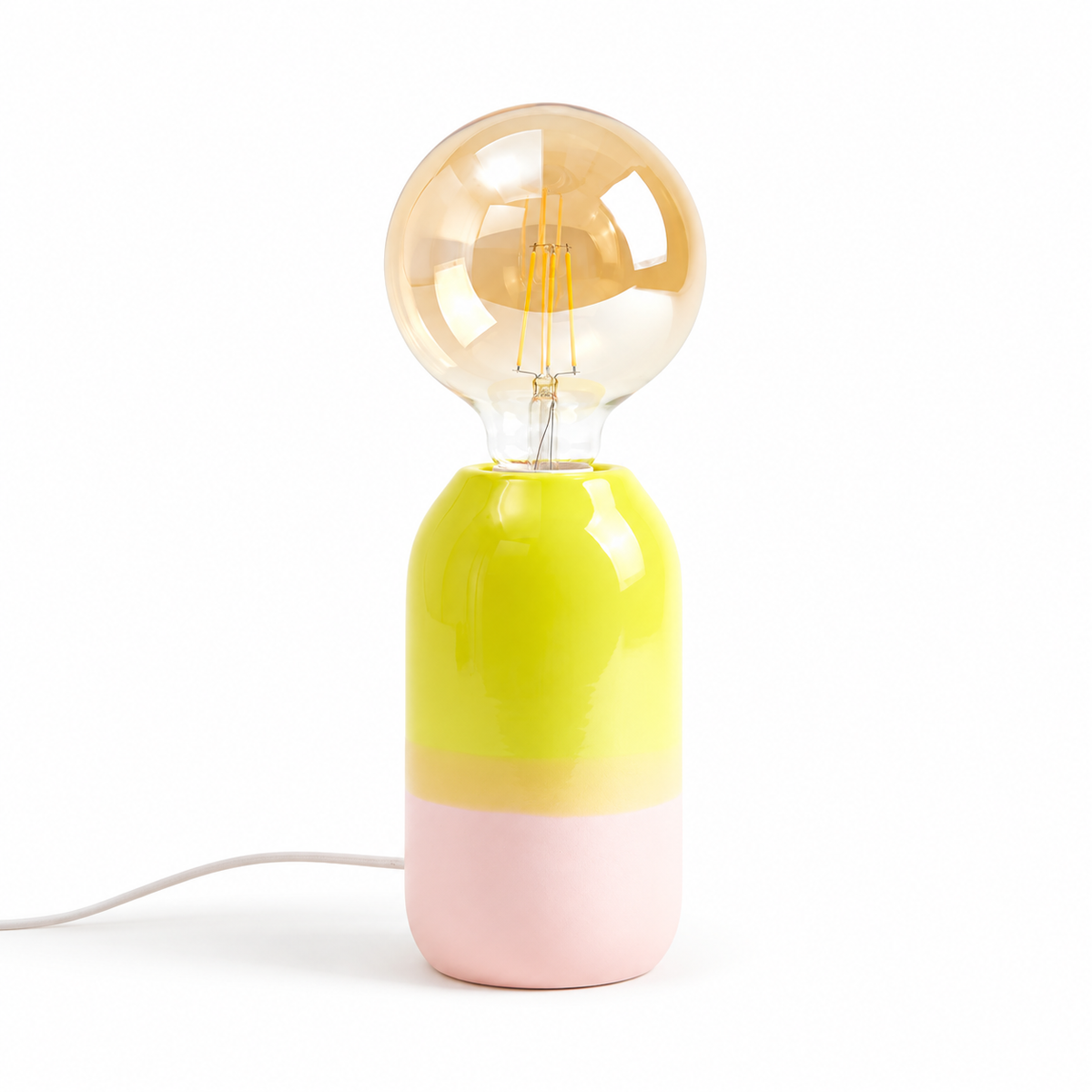 Lampada Farol Motel a Miio in gres bicolore giallo lime e rosa, con lampadina a globo ambrata, su fondo bianco.