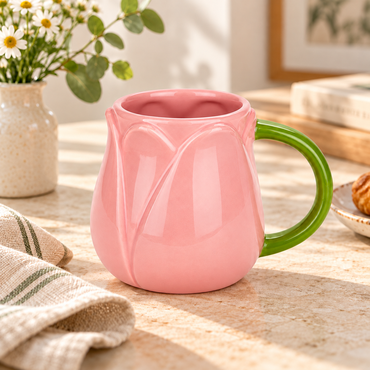 Mug Tulip Balvi rosa con manico verde, ambientata su una tavola in tonalità naturali accanto a fiori bianchi.