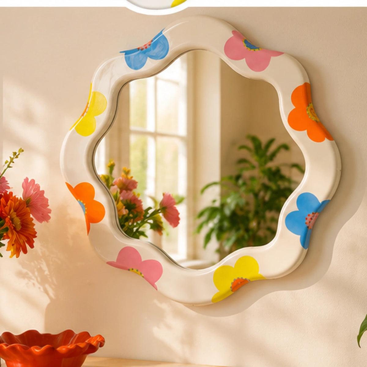 Specchio Marta Qué Rico floreale multicolore appeso a una parete beige, in un ambiente con fiori e complementi decorativi.