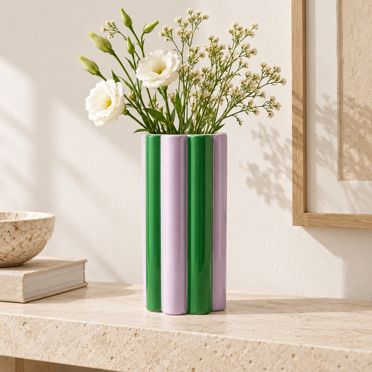 Vaso Arturo Qué Rico verde e lilla con fiori bianchi, ambientato su una consolle in pietra in un soggiorno luminoso.