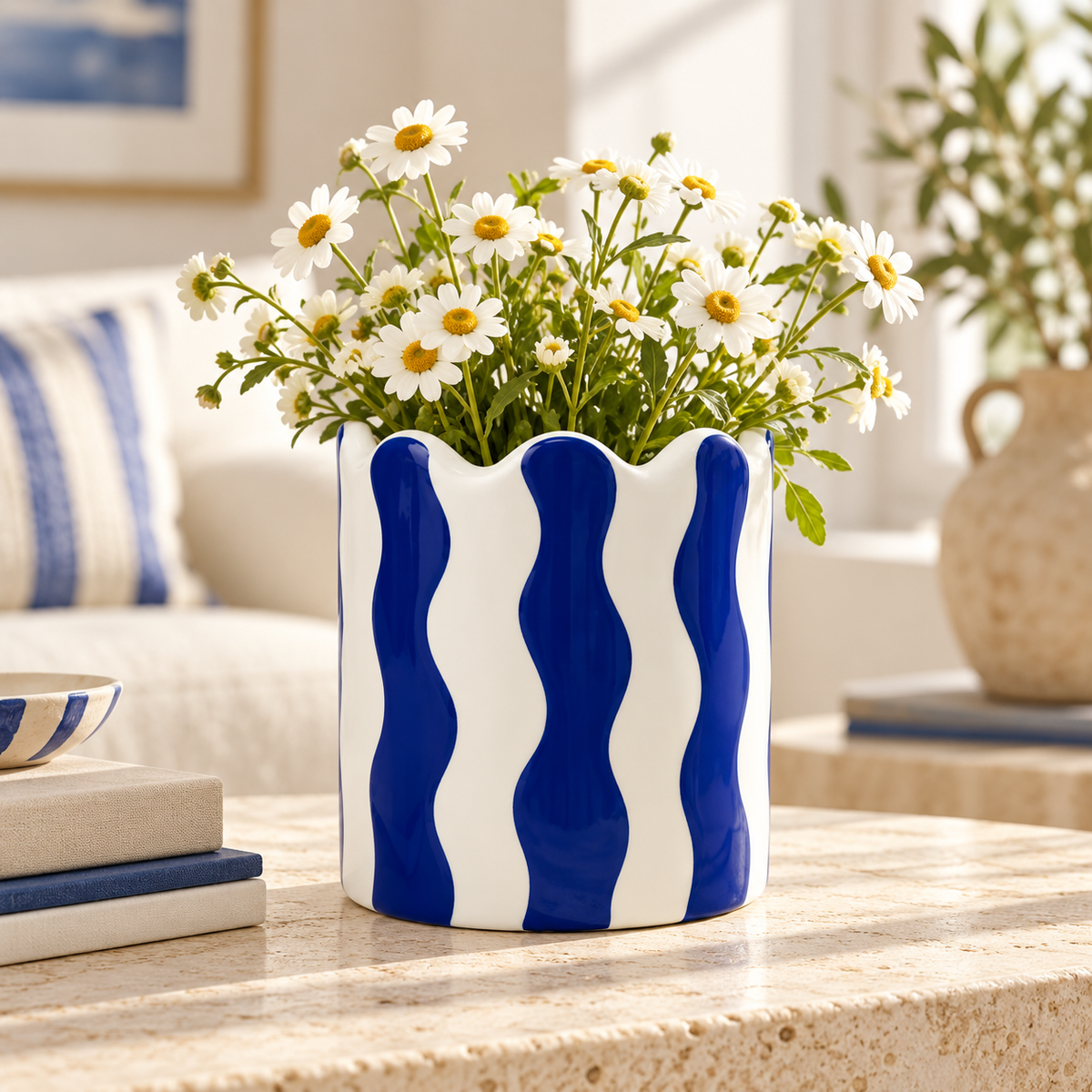 Vaso Small Qué Rico bianco e blu con margherite bianche, ambientato su un tavolino in un soggiorno contemporaneo.