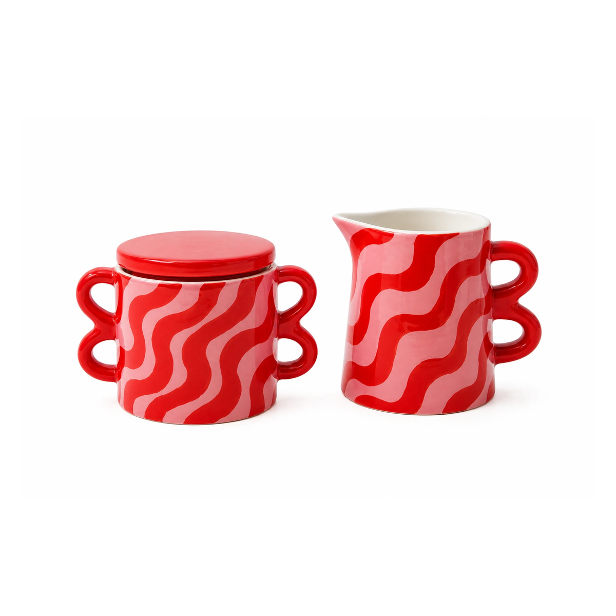 Set in ceramica Que Rico Nata Clarita composto da zuccheriera con coperchio e lattiera, decorazione ondulata rosa e rossa, fotografato su sfondo bianco.