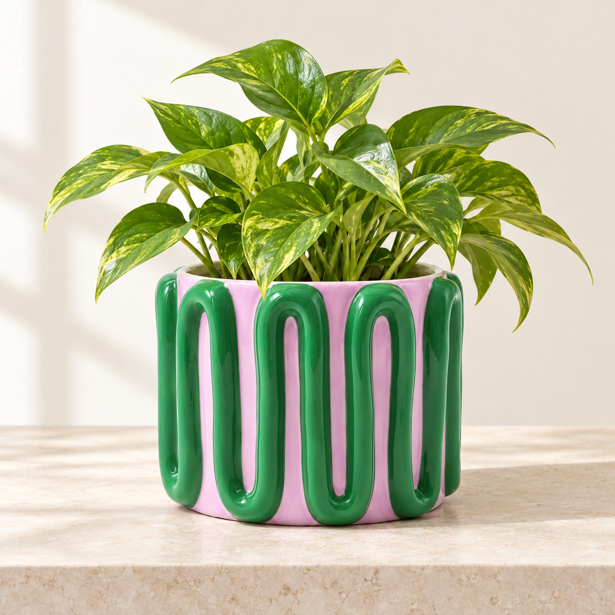 Cachepot Estefanía Qué Rico lilla e verde con pianta pothos dalle foglie variegate, ambientato su un piano in pietra chiara.