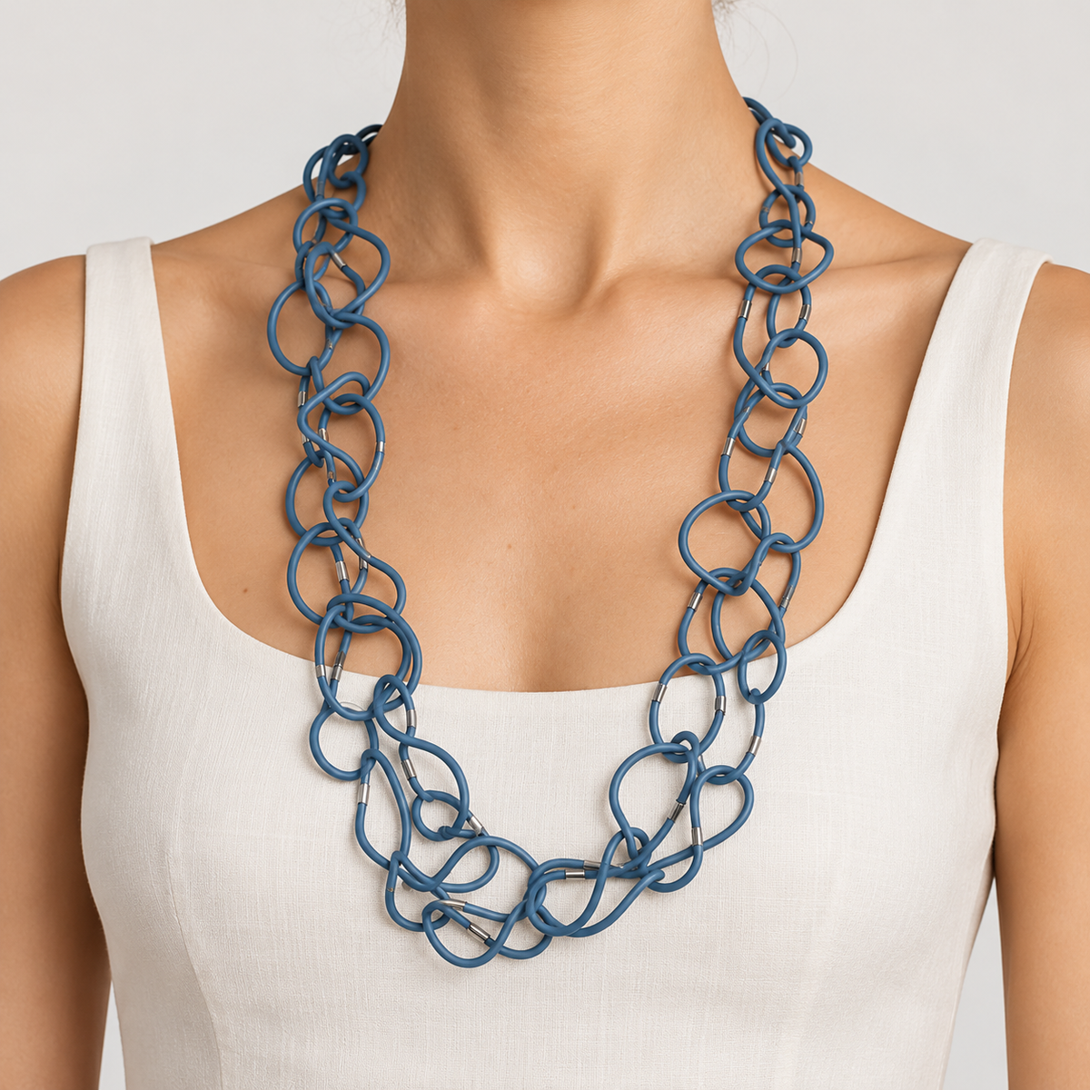 Collana Memory Color blu modellabile con anelli intrecciati e dettagli metallici, indossata su un top bianco.
