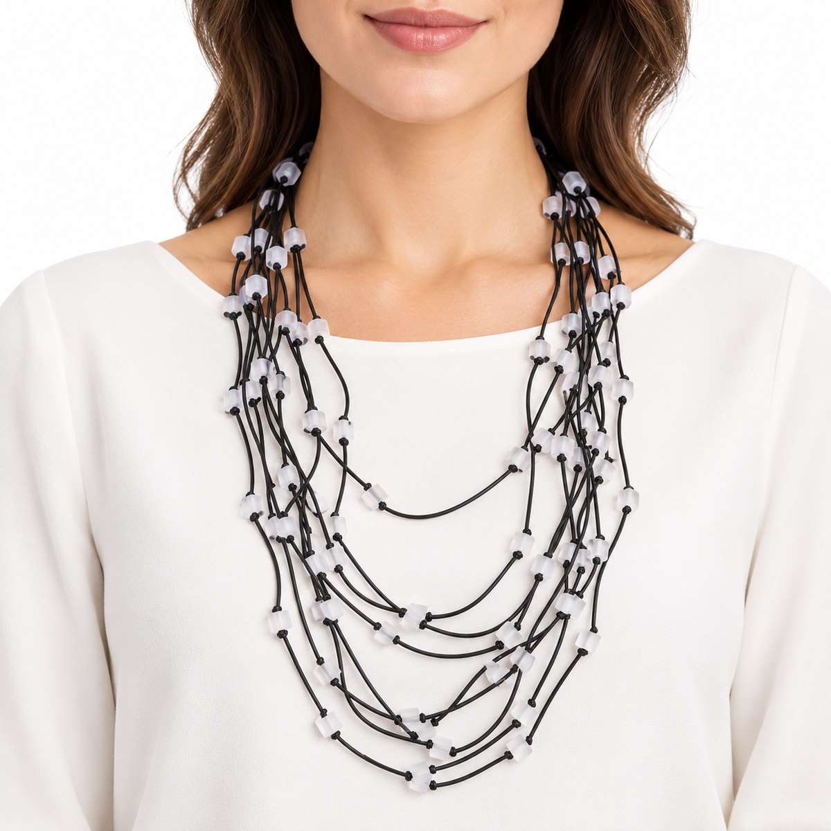Collana Scuba Lunga multifilo in caucciù nero con micro cubi bianco opalino, indossata su un abito bianco.