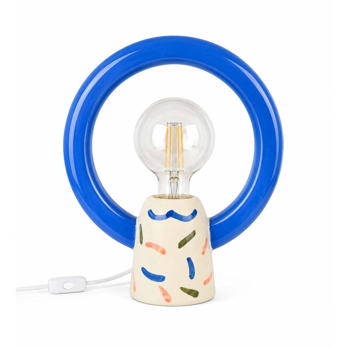 Lampada da tavolo Matias Joyful Jumble di Qué Rico con anello circolare blu, base decorata multicolore e lampadina centrale, alta 26 cm.