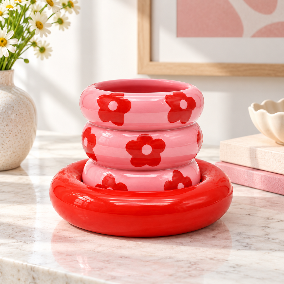 Tazza Casimiro Qué Rico rosa con fiori rossi e piattino coordinato, ambientata su un tavolo in pietra chiara con libri e fiori.