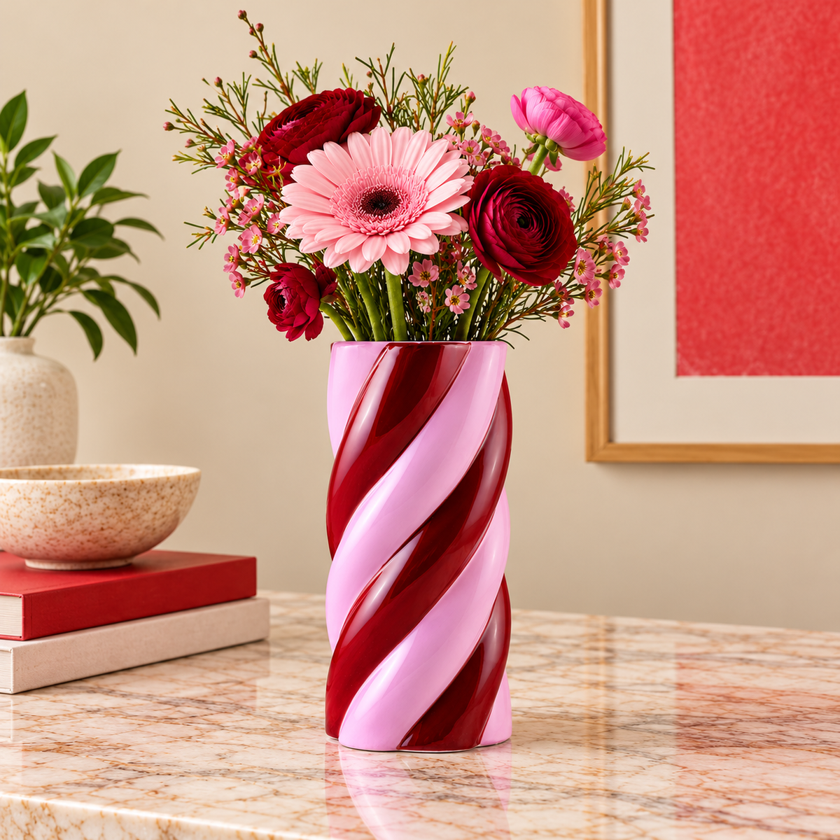 Vaso Camila Amor del Color Qué Rico a spirale rosa e bordeaux, con composizione floreale sui toni del rosa, ambientato su una consolle in pietra.