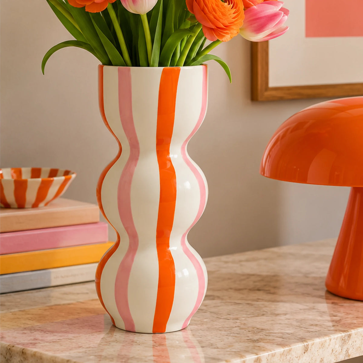 Vaso Raquelita Rayas Bailarinas Qué Rico con tulipani rosa e fiori arancioni, ambientato su una consolle in pietra in un soggiorno contemporaneo.