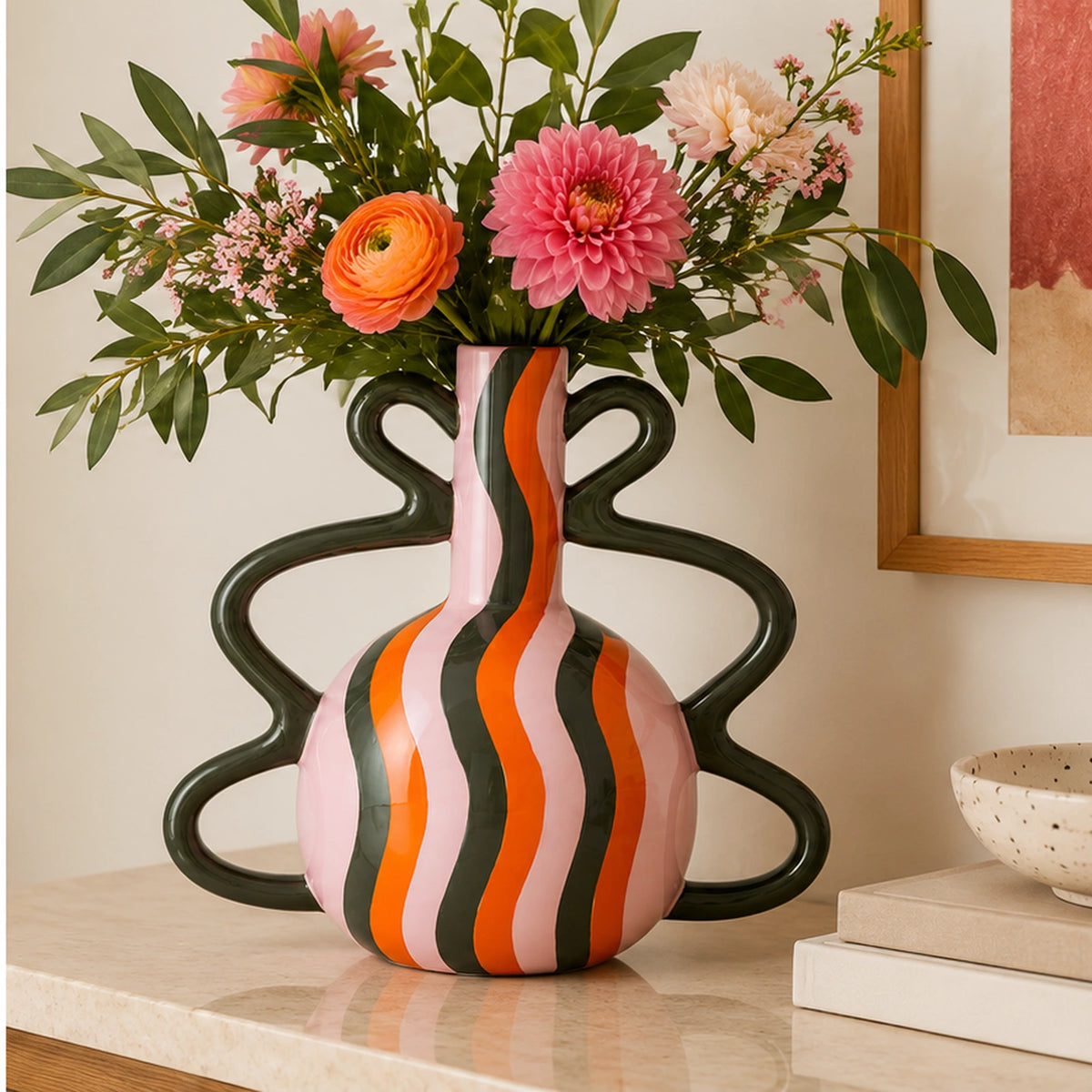 Vaso Sofía Qué Rico multicolore con fiori rosa e arancioni, ambientato su una consolle in pietra chiara in un interno contemporaneo.